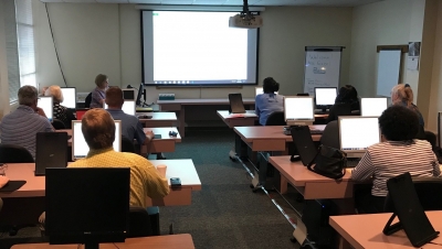People viewing a presentation being given and taking notes